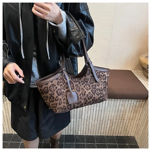 Detail of leopard print tote bag with dark brown leather straps on female model