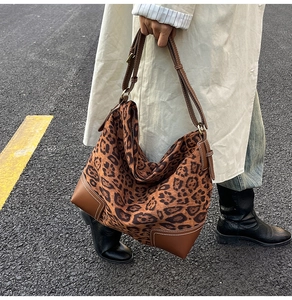 Outdoor street style shot of a leopard print tote bag with brown leather base and stitching