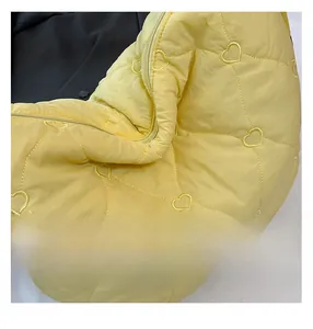 Close-up of bright yellow nylon crossbody bag with quilted heart pattern and zip detail