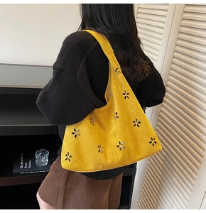 Détail du sac bandoulière en daim jaune moutarde avec motif floral découpé au laser