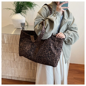 Detail of large leopard print tote bag styled with a green jacket and white skirt