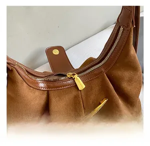 Gros plan sur les garnitures dorées et la texture en daim marron du sac à bandoulière
