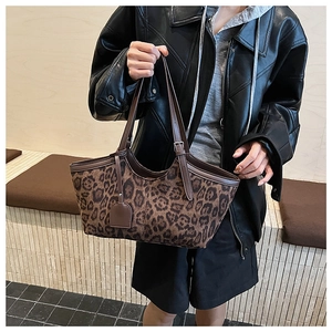 Detail of leopard print tote bag featuring brown leather straps and adjustable metal buckle