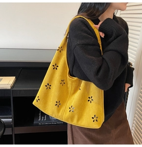 Gros plan détaillé du motif floral évidé jaune sur le sac cabas en daim minimaliste