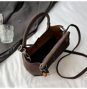 Top view of dark brown bucket bag with beaded charm and interior space detail