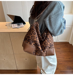 Close-up of leopard print tote bag featuring brown leather trim and white contrast stitching