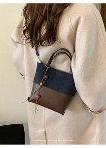 Close-up of retro bucket bag with navy suede, brown leather, and beaded charm detail