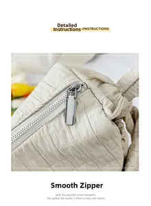Macro shot of smooth silver metal zipper on cream quilted tote bag with pleated texture
