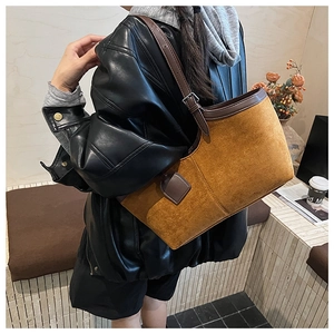 Detail of vintage brown suede tote bag with leather straps and metal buckle on table