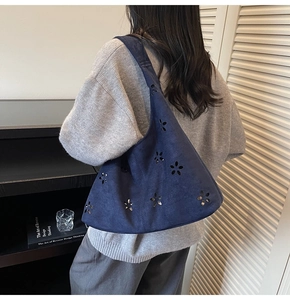 Détail de motifs floraux découpés au laser sur un sac hobo en daim bleu marine