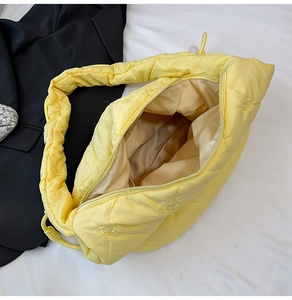 Detail of yellow quilted dumpling bag with heart embroidery and padded shoulder strap