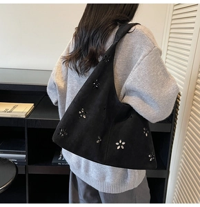 Détail du sac porté épaule en daim noir avec rivets métalliques ajourés en fleur