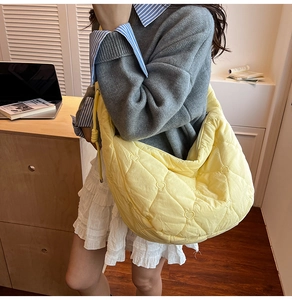 Detail of yellow quilted tote bag featuring unique heart stitching and oversized moon shape