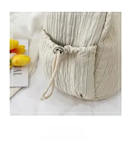Detail view of the drawstring side pocket and quilted fabric texture on the beige tote bag