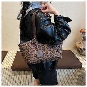 Leopard print shoulder bag with brown leather strap styled on model in urban outfit