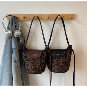 Detail of leopard print bucket bags with leather flap and drawstring closure on wooden hook