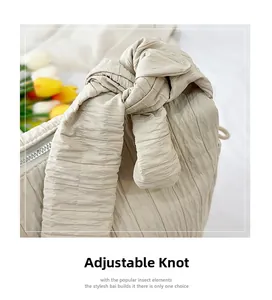 Detail of adjustable knotted shoulder strap on beige pleated texture tote bag