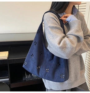Détail d'un grand sac cabas en daim bleu marine avec des motifs floraux découpés au laser