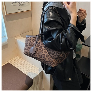 Detailed view of leopard print tote bag with brown leather straps on shoulder