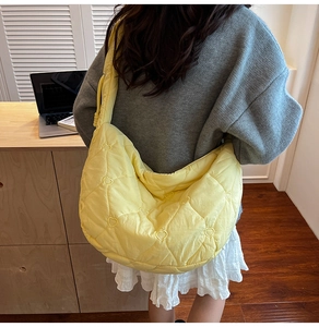 Detail of yellow quilted dumpling bag featuring heart embroidery and soft texture