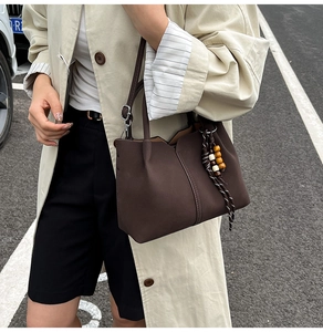 Detail of dark brown leather bucket bag with decorative colorful wood beads and V-cut top