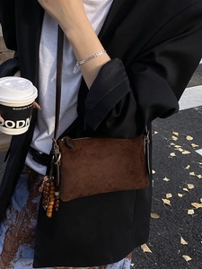 Bolso bandolera de ante mate marrón con borla de cuentas de madera en modelo de calle
