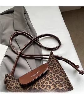 Detail of leopard print bucket bag featuring brown leather flap and stylish cord strap