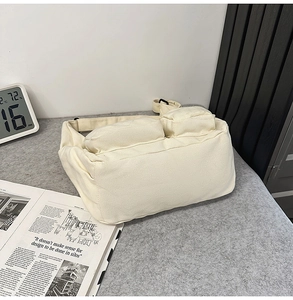 Gros plan d'un sac fourre-tout en toile crème avec deux poches et bandoulière réglable
