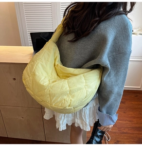 Detailed view of the yellow quilted shoulder bag featuring heart embroidery texture