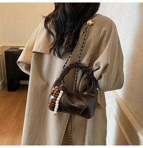 Detail of coffee crescent bag with pleated handle and wooden bead tassel accessory