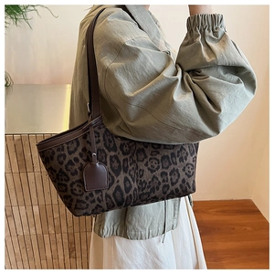 Detail of vintage leopard print suede tote bag with brown leather straps and charm