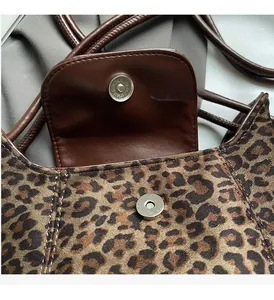 Close-up of leopard print suede bucket bag with brown leather flap and silver magnetic buckle