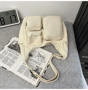 Détail du sac bandoulière en toile blanc cassé avec poches utilitaires et large sangle
