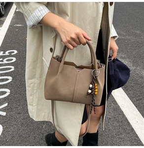 Close-up of brown suede tote bag with decorative wooden beads and sleek leather handles