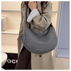 Close-up of gray pleated quilted texture and crescent moon structure on crossbody bag