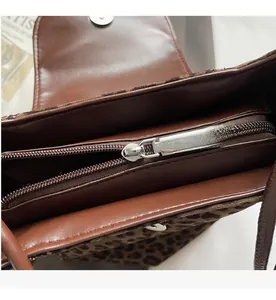 Macro shot of smooth metal zipper and leather lining on leopard print bucket bag