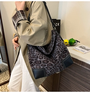 Detail showing the leopard print tote bag with reinforced leather corners and white stitching