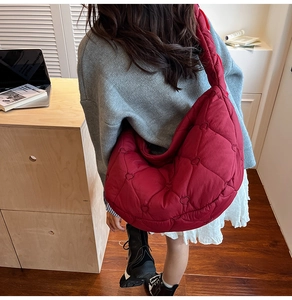Rear view of model wearing a large burgundy dumpling bag with heart quilted pattern