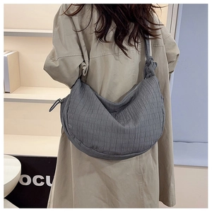 Detail of greyish-blue hobo bag featuring pleated texture and elegant knotted shoulder strap