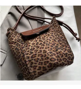 Detailed macro view of leopard print suede bucket bag with brown leather flap and strap
