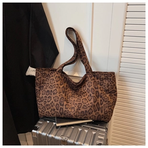 Detail shot of leopard print canvas tote bag resting on a silver suitcase for travel