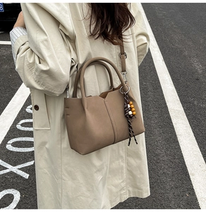 Macro view of matte leather handbag texture with retro wooden bead and woven tassel detail
