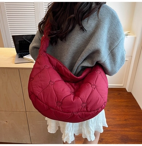Macro shot of burgundy quilted shoulder bag featuring premium heart-shaped embroidery detail