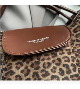 Detail of leopard print suede texture and brown leather flap with embossed fashion logo