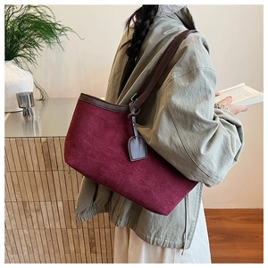Detail of burgundy suede tote bag with slim brown shoulder straps and vintage texture