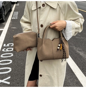 Detail of mocha brown matte leather bucket bag set with beaded pendant and shoulder strap