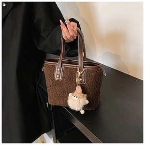 Detailed texture of brown plush faux fur bucket bag with leather handles and charm