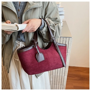 Detail of burgundy faux suede tote bag with brown leather handles and premium stitching