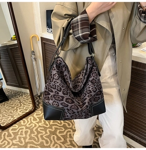 Detailed view of leopard print tote bag featuring black leather corners and contrast stitching