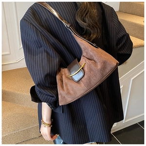 Détail d'un sac à bandoulière en daim marron avec boucle en métal doré sur un blazer